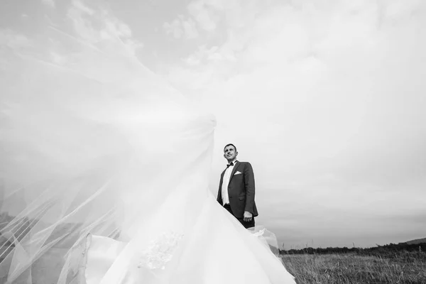 groom in suit behind flying wedding dress on a black and white photo