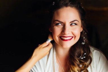 Güzel bir saç modeli ve şehvetli makyaj ve makyaj fırçası ile bir makyaj sanatçının el ile mutlu gelin