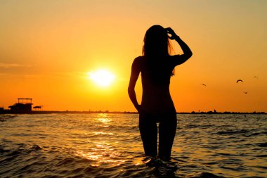 Güzel uzun modeli gün doğumu sırasında okyanusun suda ayakta orada silüeti
