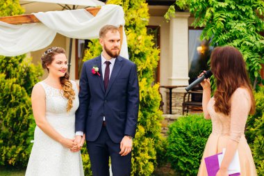 Güzel bir elbise içinde gelin damat elinde tutan ve mikrofon konuşuyor töreni ustası dinlemek