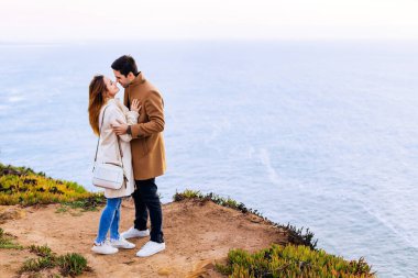 Okyanusta birbirine aşık çift yüz yüze duruyor. Adam gözlerini kapatan bir kıza sarılıyor ve onlar da onu öpmek istiyor.