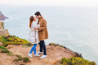 Adam gözlerini kapatan bir kız hugs ve okyanus kıyısında öpmek istiyorum