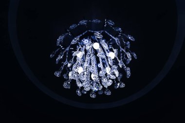 Koyu tavanda ampulleri olan güzel kristal bir avize.