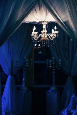tül ve ampuller ile avize tente. Şamdanlar beyaz bir kaide üzerinde mum
