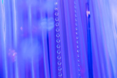 Mavi tülün arka planında şeffaf çakıl taşları olan zincirler