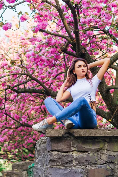 Menina Senta Pilar Pedra Cerca Cruza Pernas Fundo Árvore Flor — Fotografia de Stock