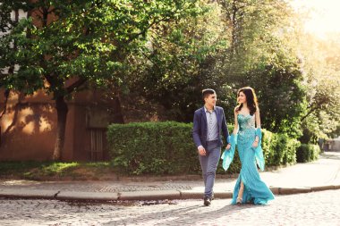 adam ve şenlikli giysili kızı el ele tutuşup şehir sokakta bakıyoruz