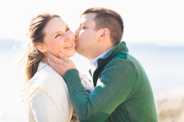 Close-up of a guy sensually kisses a girl on her cheek and she smile