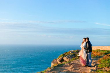 Bir adam bir kadın arka taraftan kayalık okyanus kıyısında hugs