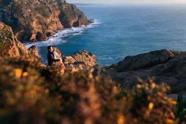 kayalık sahil güneş ışığı ve okyanus. Bir erkek bir kadın arka taraftan okyanus kıyısında hugs