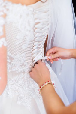 Nedime gelinliğin arkasında yay-düğüm yapar. b