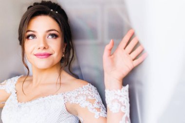 Gelin beyaz curtai altında güzel bir makyaj ile beyaz elbiseli