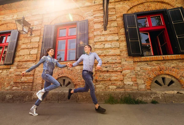 Το ερωτευμένο ζευγάρι Κρατήστε τα χέρια και να τρέξει στο πεζοδρόμιο κοντά σε ένα bri — Φωτογραφία Αρχείου
