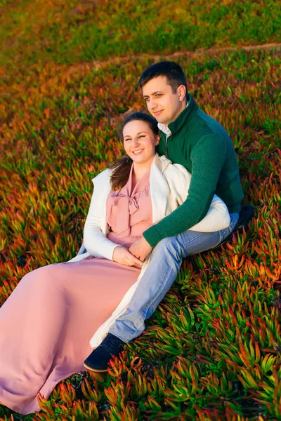 Un homme étreint une femme et ils s'assoient sur l'herbe et sourient — Photo