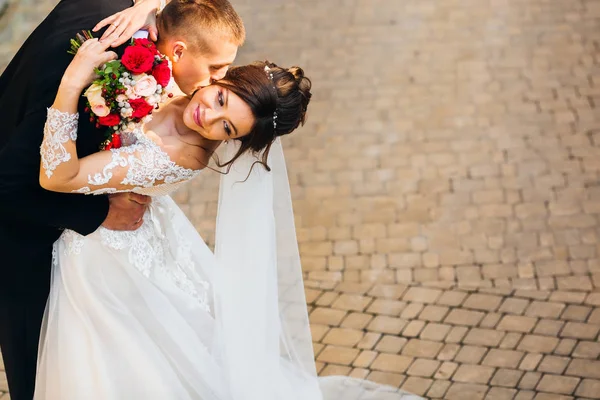 Šťastní novomanželé líbání na pozadí na chodník. b — Stock fotografie