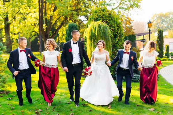 Brautjungfern mit Trauzeugen und Hochzeitspaar halten Händchen und smi — Stockfoto