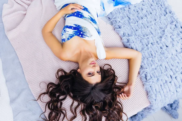 Frau mit welligem Haar liegt auf einem Bett — Stockfoto
