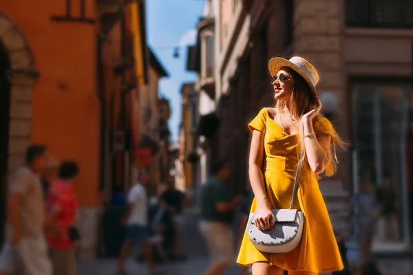 Девушка в желтом платье с сумочкой позирует на фоне — стоковое фото