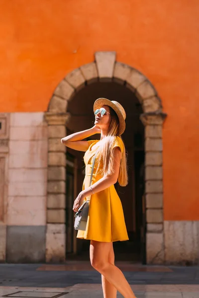 En vacker flicka i en gul klänning poserar framför fotvalvet — Stockfoto
