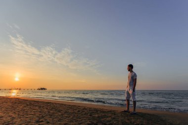 Beyaz bir T-shirt ve şort bir adam onun ellerini onun pocke tutar.