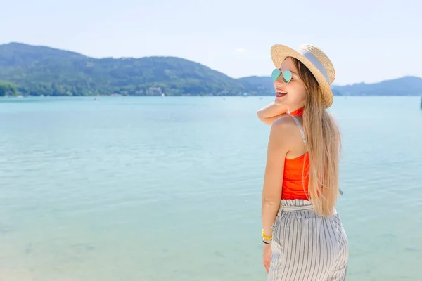 Menina em roupas de verão e óculos de sol sorrir perto do lago. montar — Fotografia de Stock