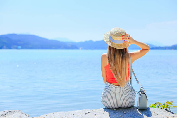 Молодая женщина сидит на берегу горного озера. лодка и длинный ч
