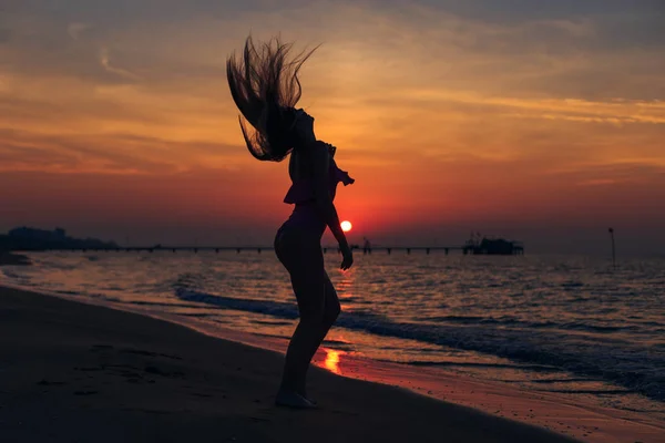 Das Mädchen im rosa Badeanzug wedelt mit den Haaren am Strand. Meer und — Stockfoto