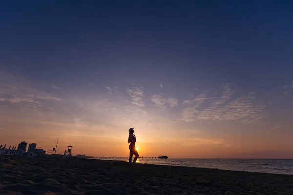 Meer und Sonnenuntergang. Mädchen Silhouette in Bootsfahrer am Sandstrand Anzeige — Stockfoto