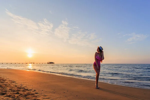 Sexy dziewczyna pozuje na plaży na tle słońca — Zdjęcie stockowe