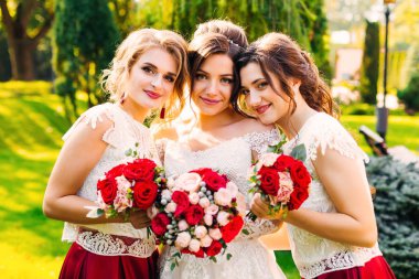 Gelin ve çiçeklerle ayakta ve sarılma nedime. Kız