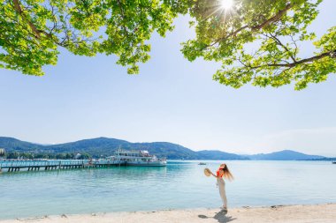 Bir kız bir göl kıyısında bir hasır şapka onun elinde tutar. gemi n