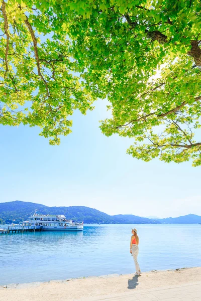 Vista posterior de una mujer se encuentra sola en el lago y las montañas en el b — Foto de Stock