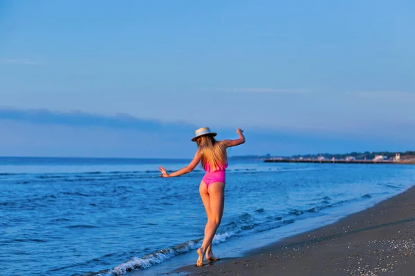 Młoda kobieta spaceru na plaży. Baw się dobrze. Dziewczyna w różowym swimsui — Zdjęcie stockowe