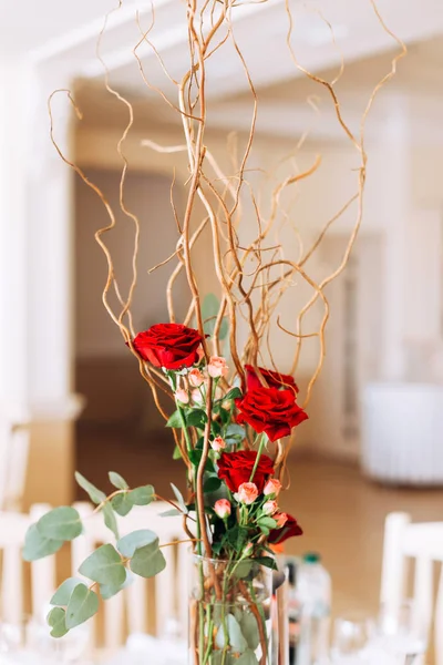 Троянди і сухі гілки в прозорій вазі на столі для гостей — стокове фото