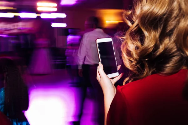 Una chica con un hermoso peinado sostiene el teléfono en su mano. c) — Foto de Stock