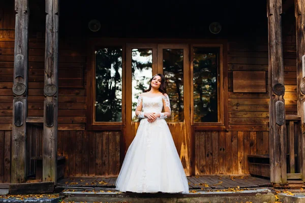 Bela noiva jovem no vestido de noiva fica no alpendre de madeira — Fotografia de Stock