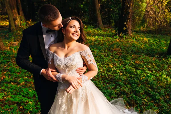 Le marié embrasse la mariée de l'arrière et veut s'embrasser — Photo