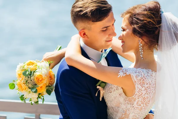 Abraço de recém-casados. A noiva mantém um buquê de casamento de ro amarelo — Fotografia de Stock