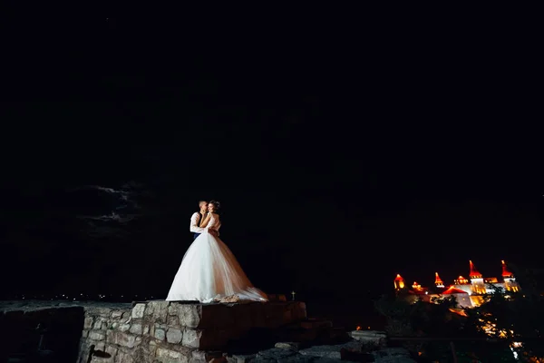 Молода весільна пара обіймається на кам'яному паркані. ніч і лі — стокове фото
