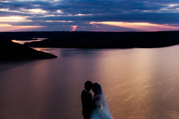 Bellissimo tramonto sul fiume. sposi che si abbracciano — Foto Stock