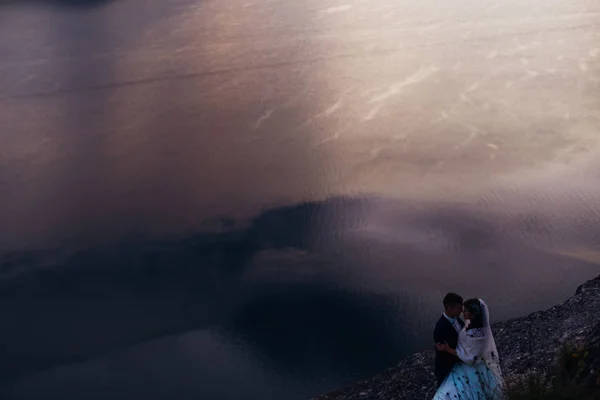 Říční voda s odraz. Novomanželé objetí na skalnaté pobřeží — Stock fotografie