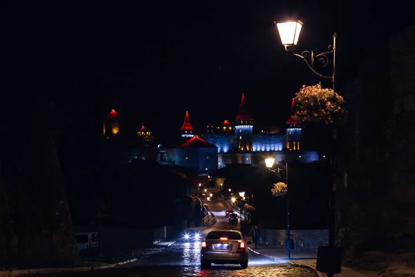 Castillo nocturno. coches y carretera iluminados por farol de calle — Foto de Stock