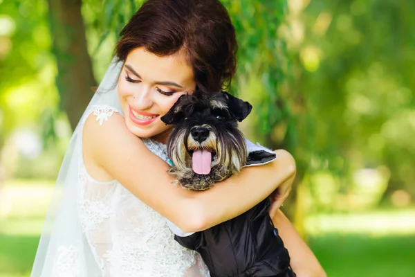 Young bride with a beautiful makeup closed eyes and hugs a dog o — Stock Photo, Image