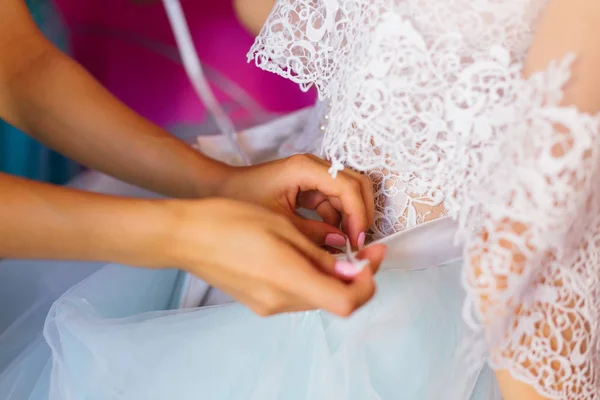Подружка невесты обвязывает бант на свадебном платье. Сзади невесты. закрыть — стоковое фото