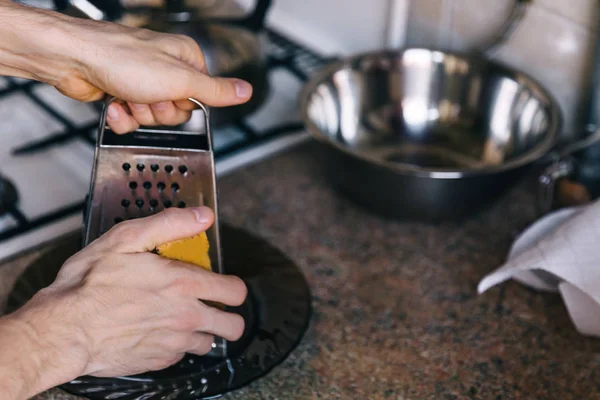 metal kitchen grater in the hands of a man. The process of cooki