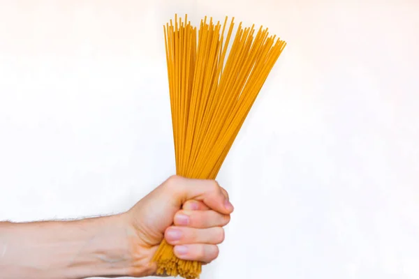 Samčí ruka obsahuje špagety na bílém podkladu. Zavřít — Stock fotografie
