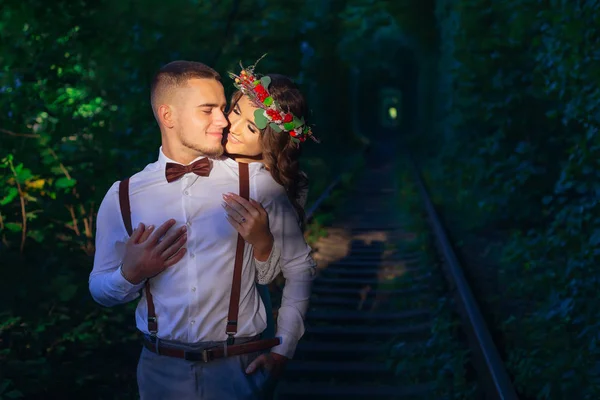 Девушка с венком на голове обнимает парня с бородой. железная дорога — стоковое фото