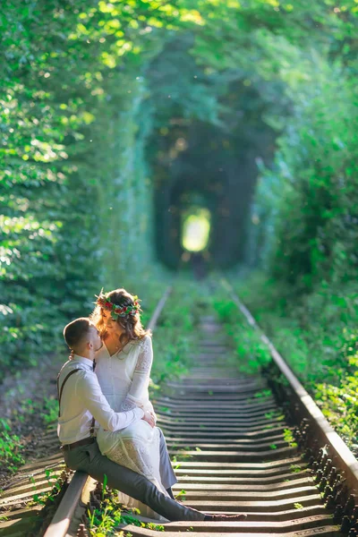 Ett par i kärlek sitter på en järnväg på bakgrunden av ett träd — Stockfoto