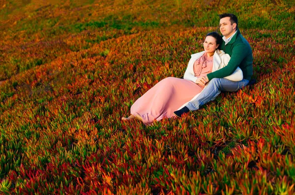Un hombre abraza a una mujer y se sientan en la hierba y miran en la d — Foto de Stock