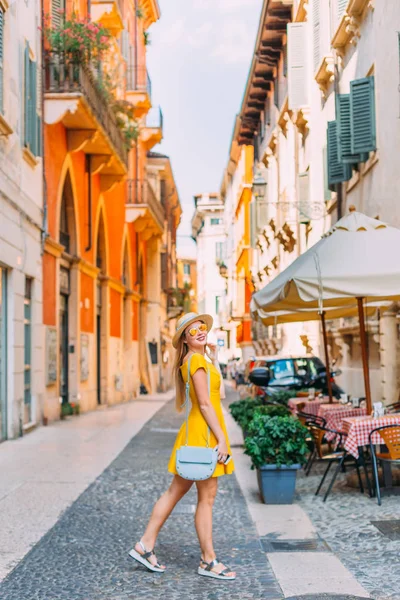 Стильная девушка в желтом платье рядом с кафе на улице — стоковое фото